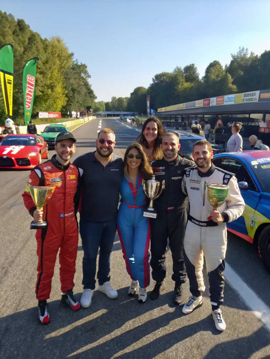 A photograph of a group of young participants proudly displaying their completed race cars at a local motorsports event, highlighting their achievements and the team's community involvement.